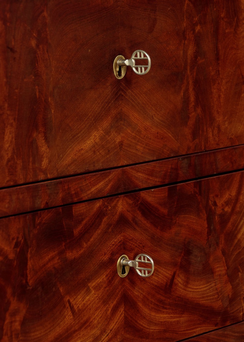 A nineteenth-century flame mahogany commode chest with four drawers, brass escutcheons, a dark slate top surface, and a plinth base. View X