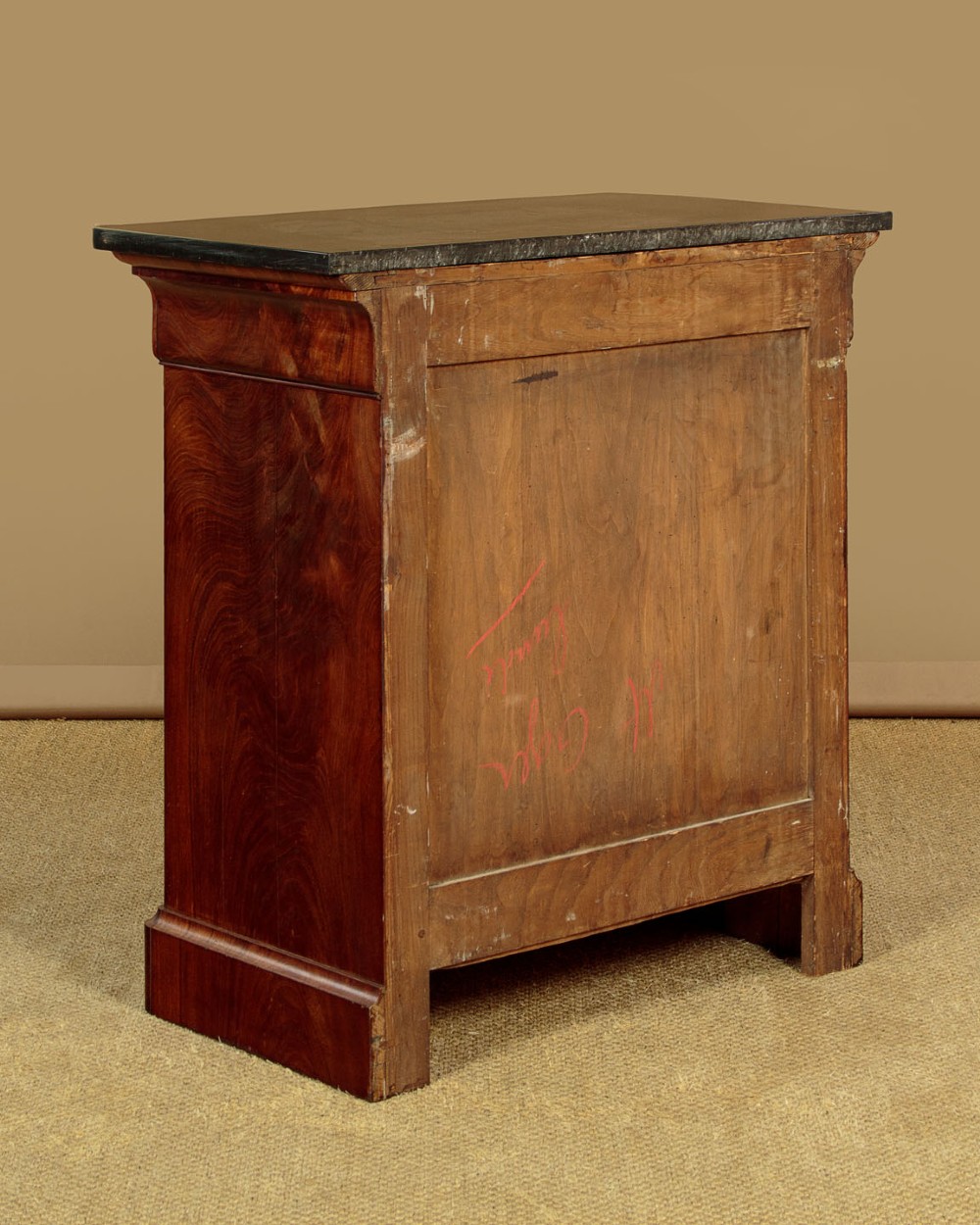 A nineteenth-century flame mahogany commode chest with four drawers, brass escutcheons, a dark slate top surface, and a plinth base. View XIII