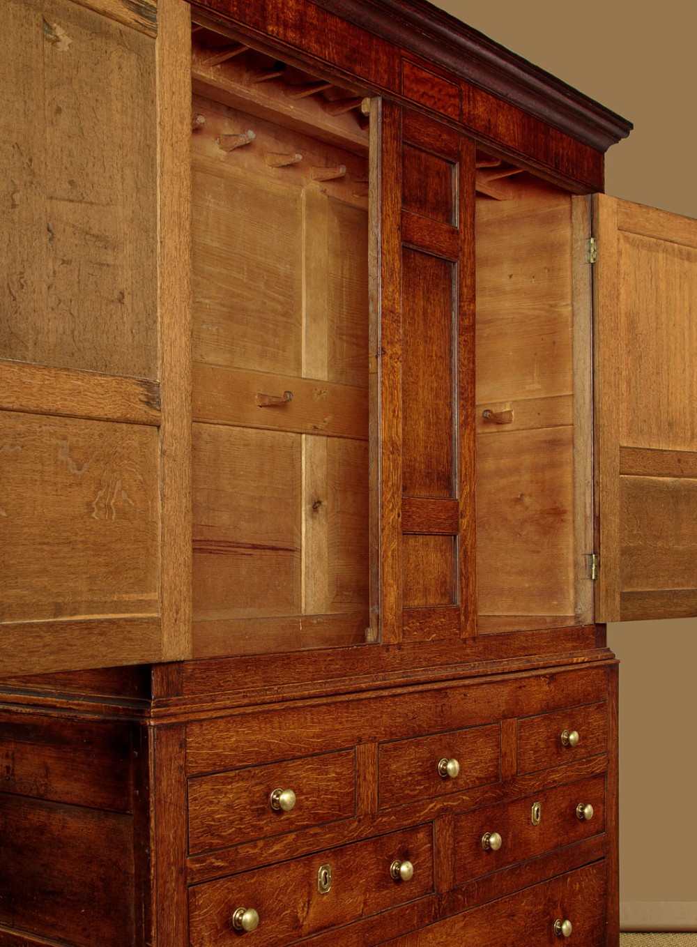 A nineteenth-century Welsh oak tack cupboard featuring a fielded twin-panel door upper section set over a chest of seven drawers with brass turned knobs. View VIII