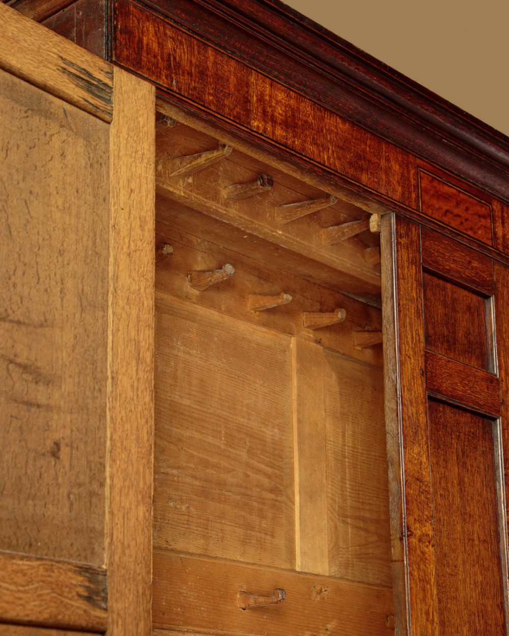A nineteenth-century Welsh oak tack cupboard featuring a fielded twin-panel door upper section set over a chest of seven drawers with brass turned knobs. View IX