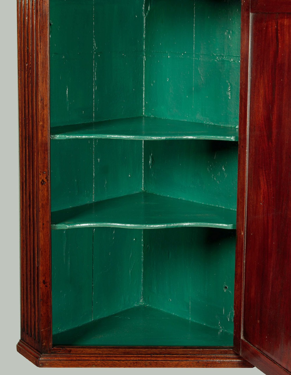 A wall-mounted Georgian mahogany corner cupboard featuring fluted pilasters, dentil moulding, and a single panelled door. View III