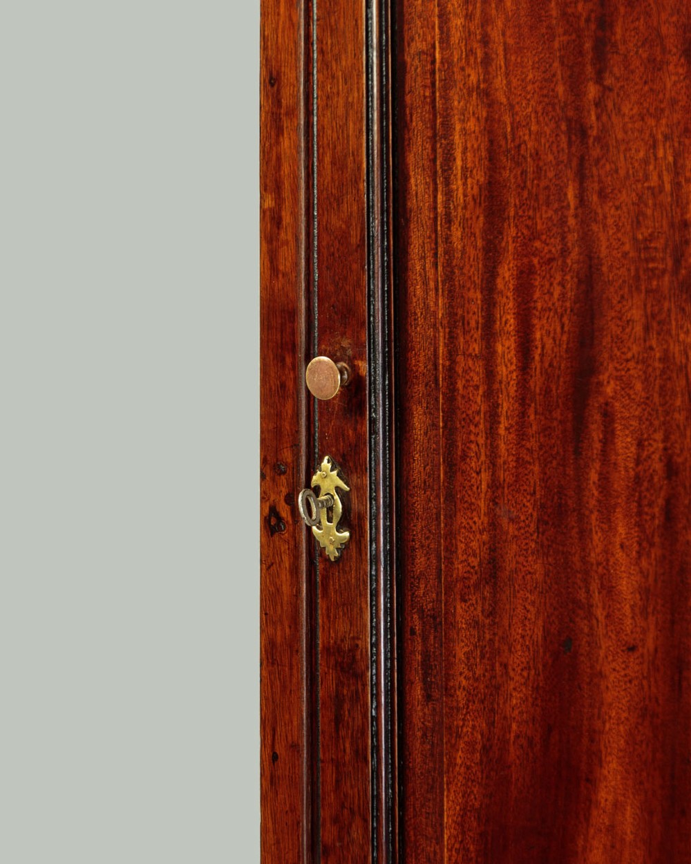 A wall-mounted Georgian mahogany corner cupboard featuring fluted pilasters, dentil moulding, and a single panelled door. View VI