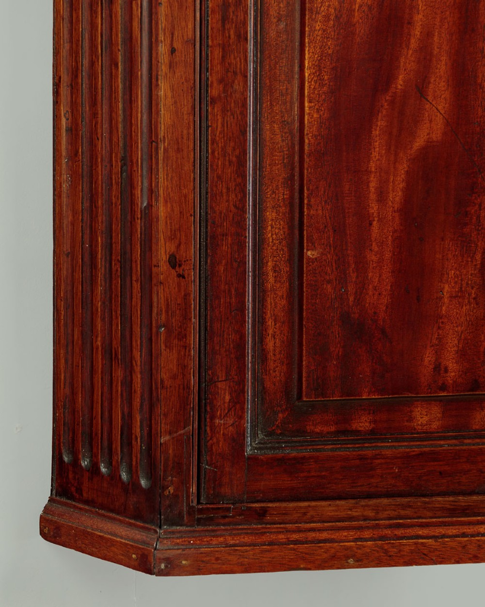 A wall-mounted Georgian mahogany corner cupboard featuring fluted pilasters, dentil moulding, and a single panelled door. View VII