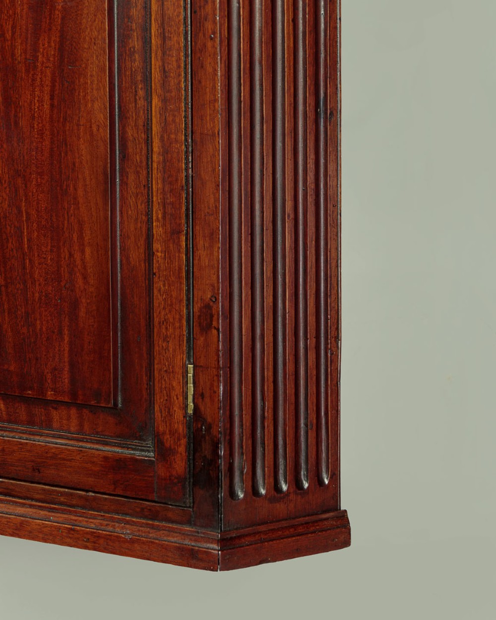 A wall-mounted Georgian mahogany corner cupboard featuring fluted pilasters, dentil moulding, and a single panelled door. View VIII
