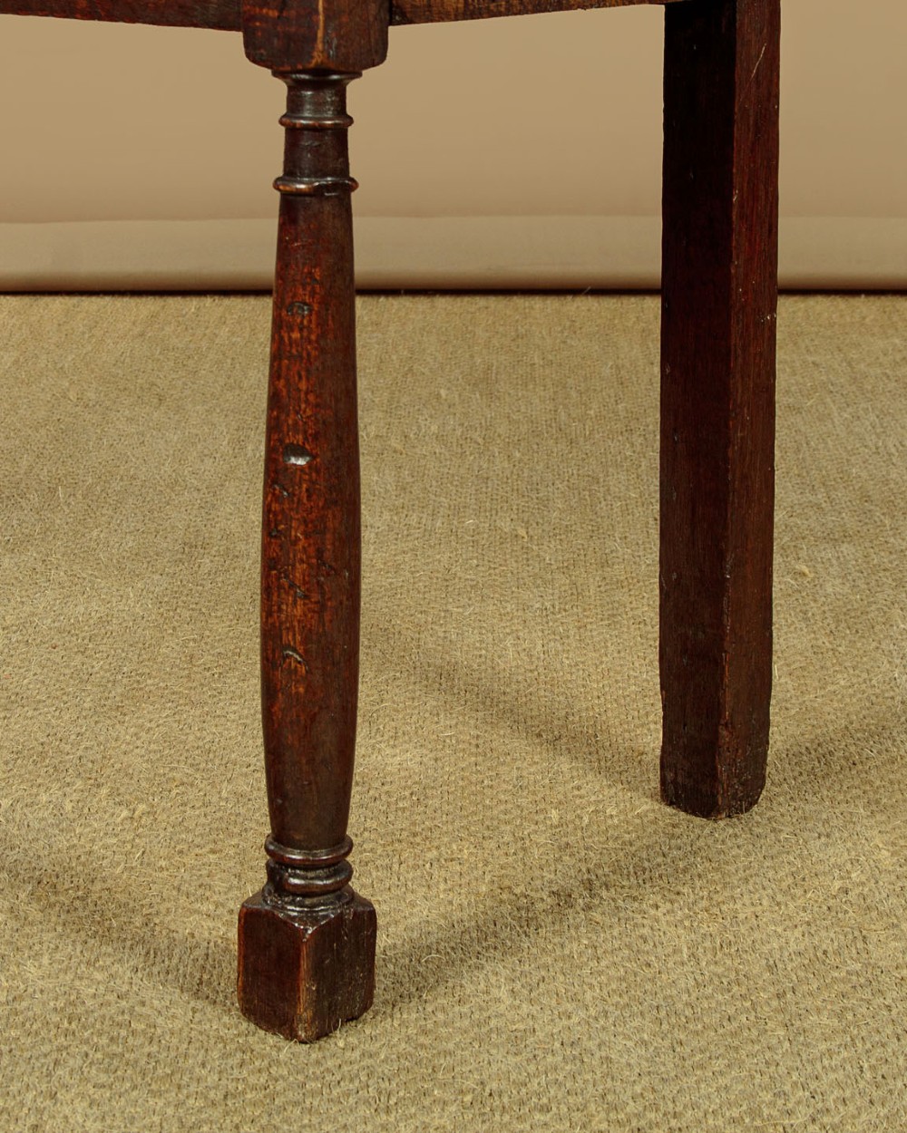 An 18th-century dark oak dresser base featuring geometric moulded drawer fronts, brass drop handles, and turned front legs. View X