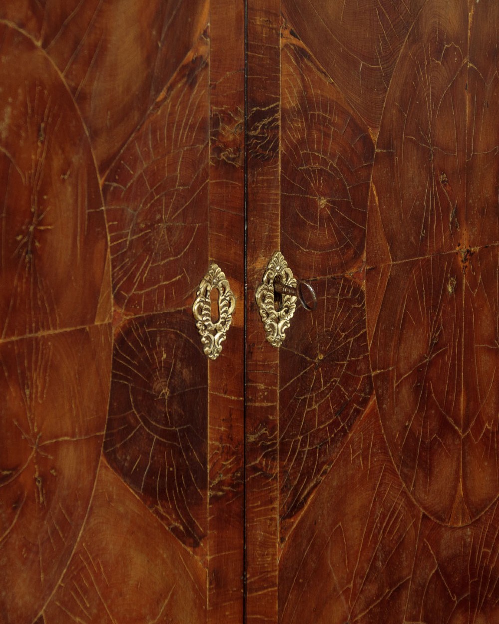 A small veneered brown wood cabinet featuring decorative door pulls, mounted atop a carved silver gilt stand with cabriole legs and a central shell motif. View VII