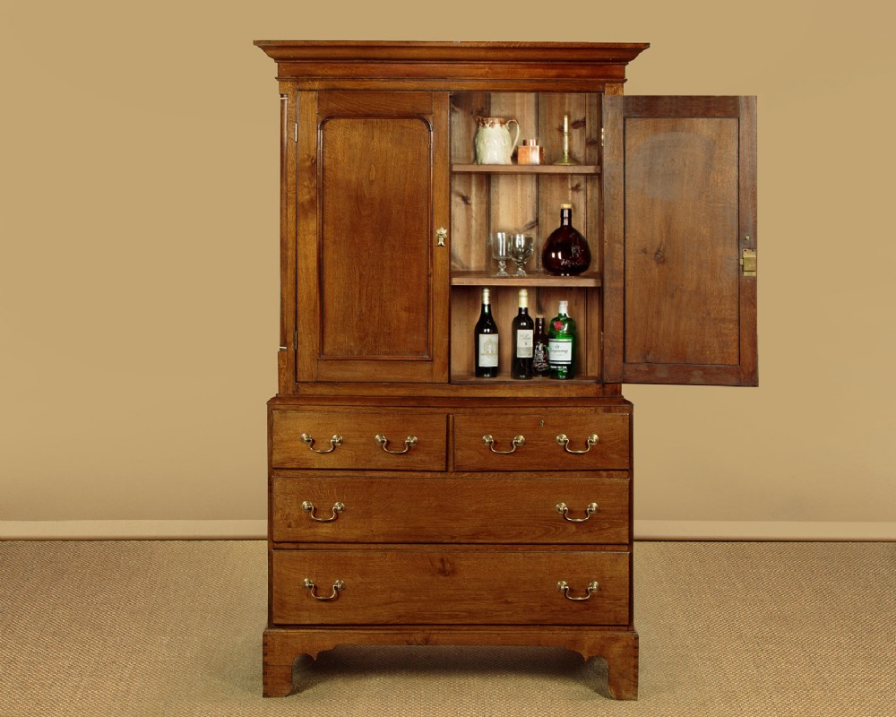 A Georgian Welsh oak press cupboard featuring a two-door upper section with fielded panels above a chest with five drawers and brass handles. View II