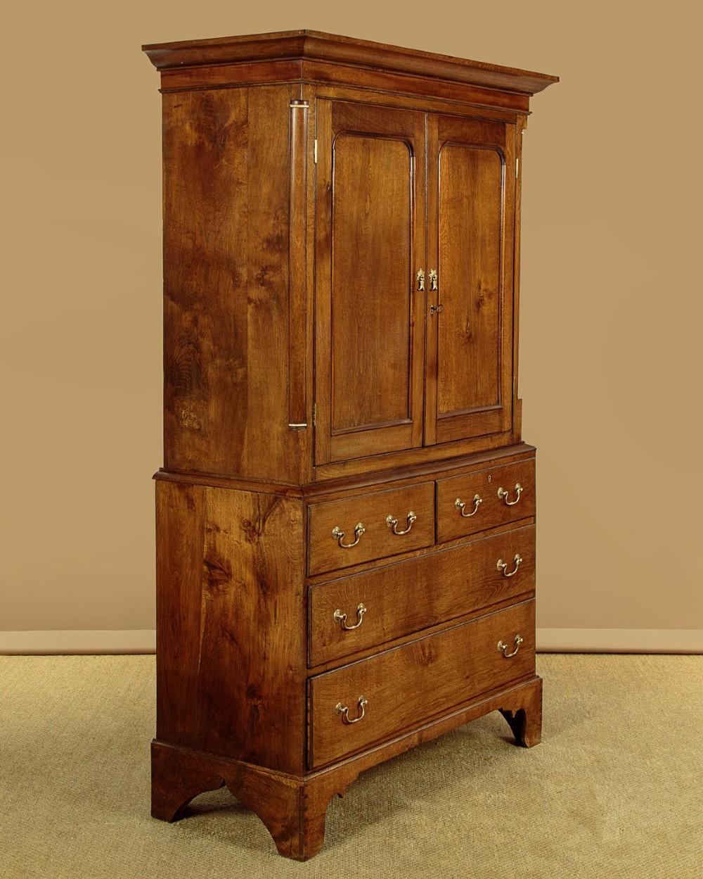 A Georgian Welsh oak press cupboard featuring a two-door upper section with fielded panels above a chest with five drawers and brass handles. View III