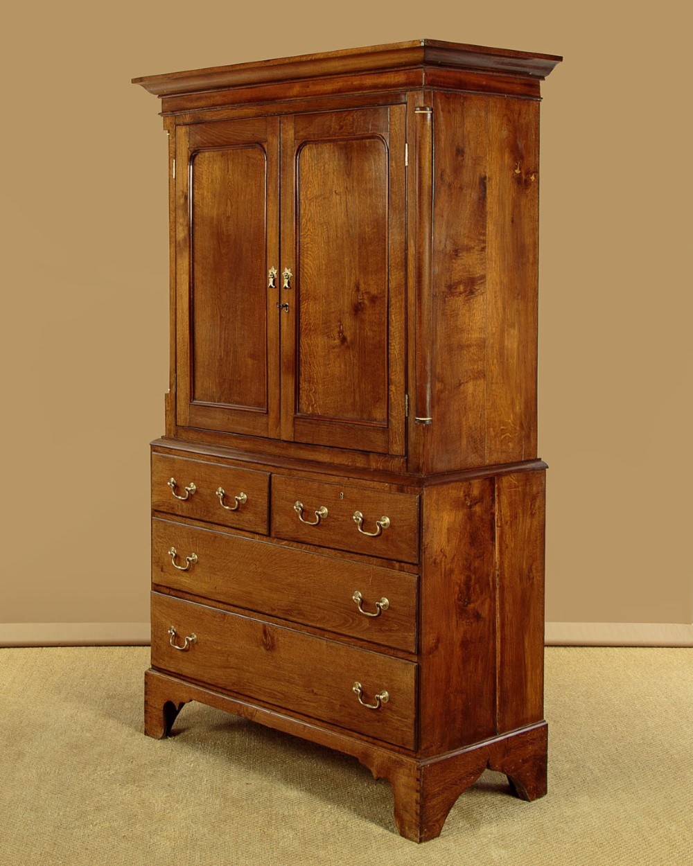 A Georgian Welsh oak press cupboard featuring a two-door upper section with fielded panels above a chest with five drawers and brass handles. View IV