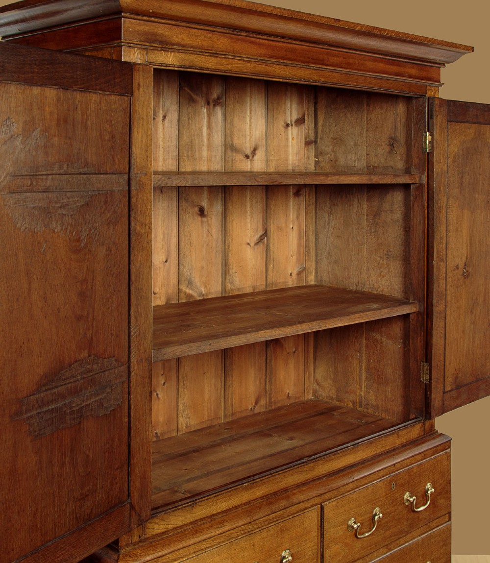 A Georgian Welsh oak press cupboard featuring a two-door upper section with fielded panels above a chest with five drawers and brass handles. View VI
