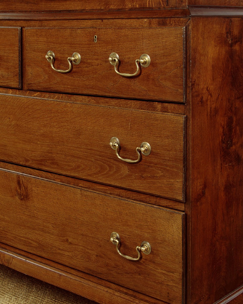 A Georgian Welsh oak press cupboard featuring a two-door upper section with fielded panels above a chest with five drawers and brass handles. View X