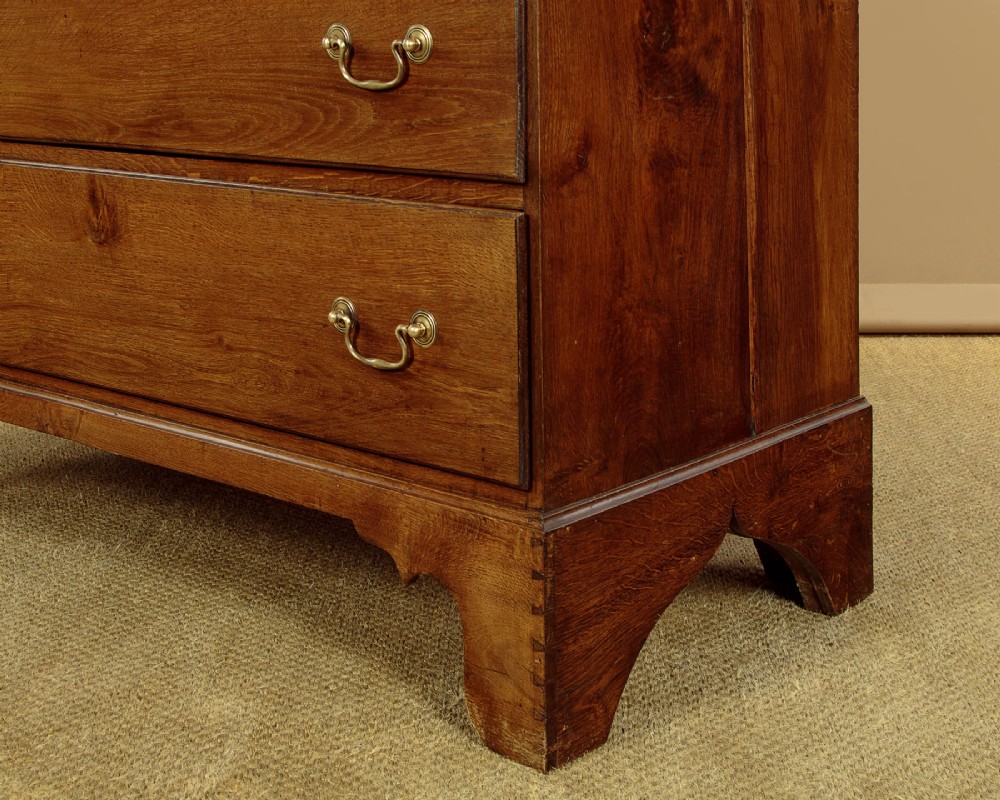 A Georgian Welsh oak press cupboard featuring a two-door upper section with fielded panels above a chest with five drawers and brass handles. View XI
