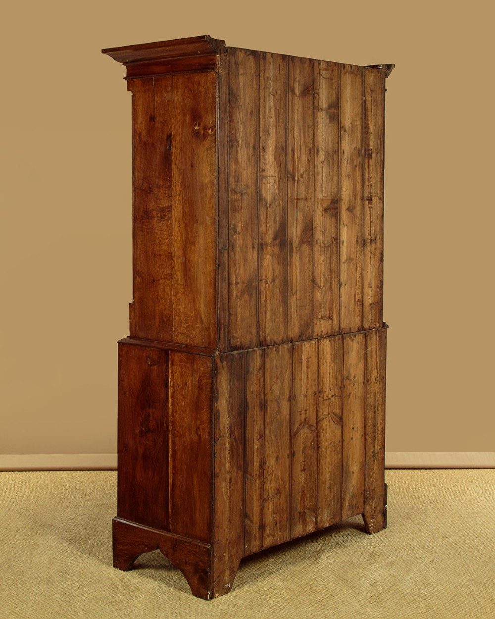 A Georgian Welsh oak press cupboard featuring a two-door upper section with fielded panels above a chest with five drawers and brass handles. View XII