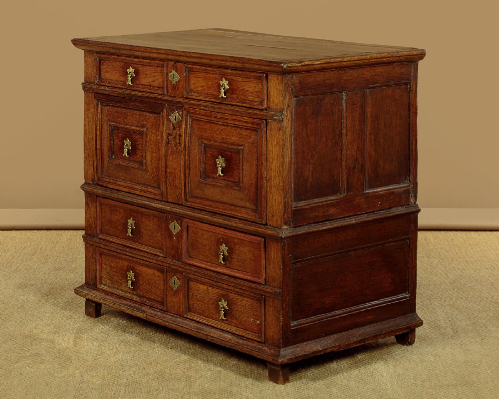 A Charles II solid oak chest of drawers featuring geometric panelled drawer fronts and brass teardrop handles. View II