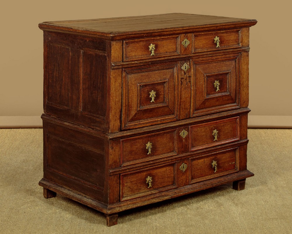 A Charles II solid oak chest of drawers featuring geometric panelled drawer fronts and brass teardrop handles. View III