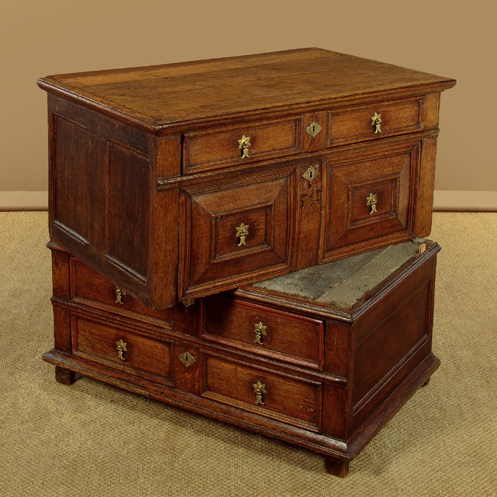 A Charles II solid oak chest of drawers featuring geometric panelled drawer fronts and brass teardrop handles. View XI