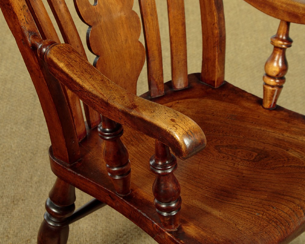 A Victorian highback wooden armchair featuring turned legs, curved armrests, a contoured seat, and a pierced back splat. View VI