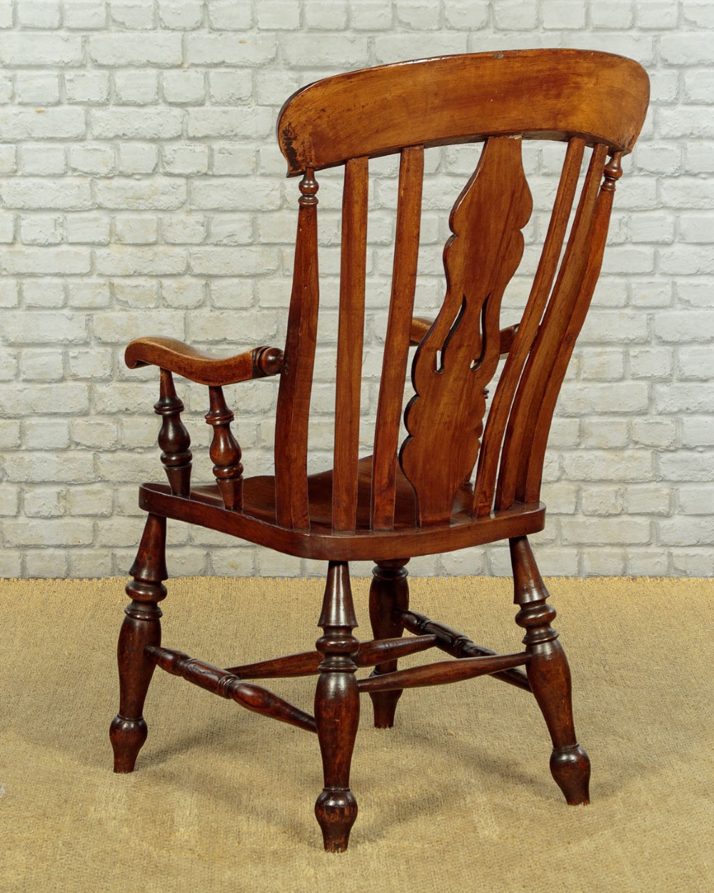A Victorian highback wooden armchair featuring turned legs, curved armrests, a contoured seat, and a pierced back splat. View X