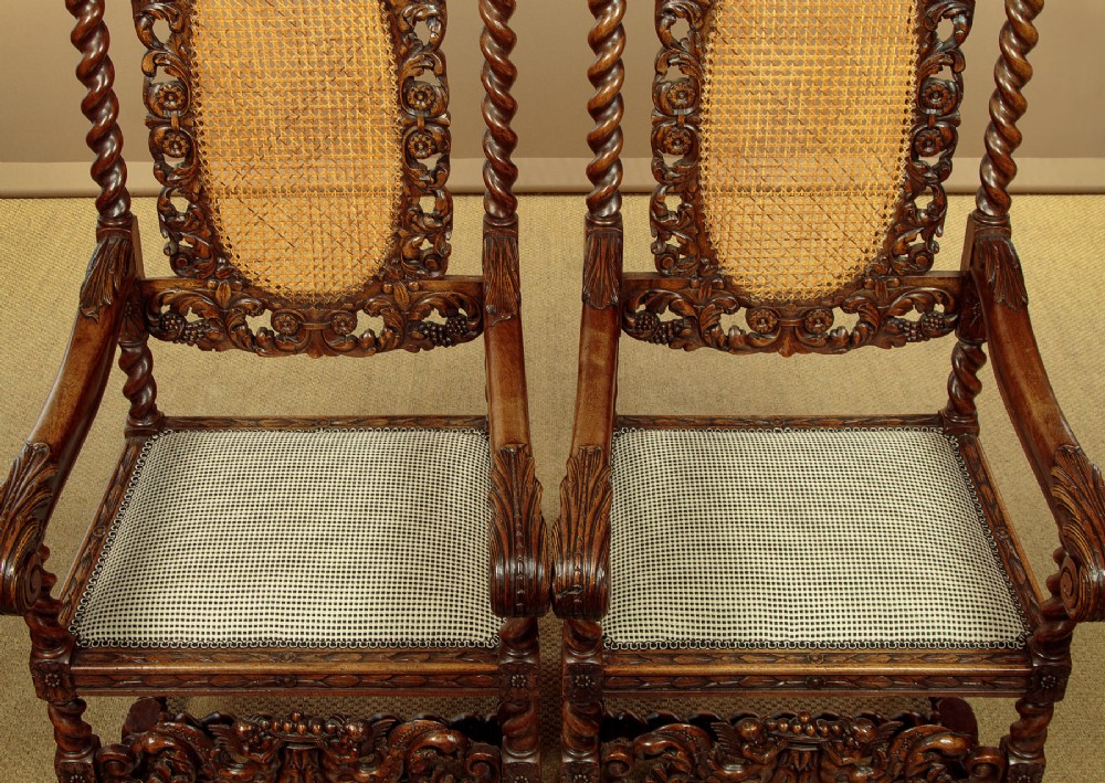 A pair of carved walnut armchairs featuring oval cane back panels, scroll armrests, and barley twist legs. View IX