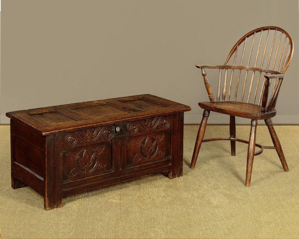A dark oak coffer from circa 1700 featuring carved panel fronts with floral motifs and a hinged wooden top. View II
