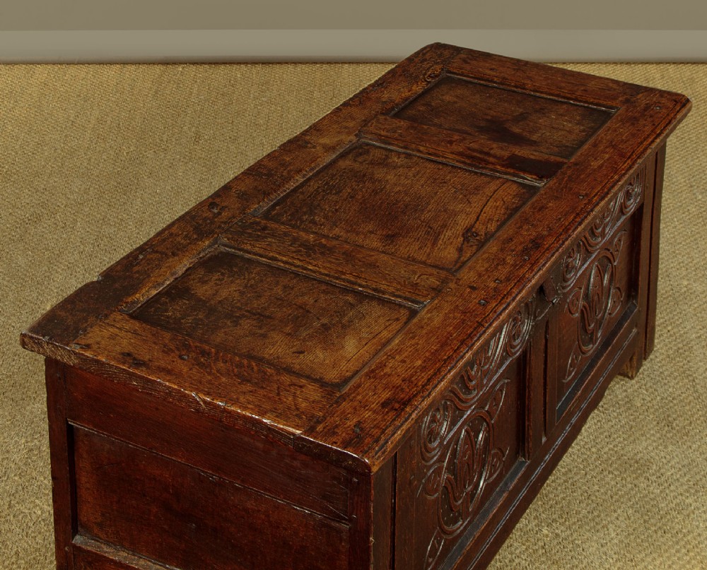 A dark oak coffer from circa 1700 featuring carved panel fronts with floral motifs and a hinged wooden top. View VI