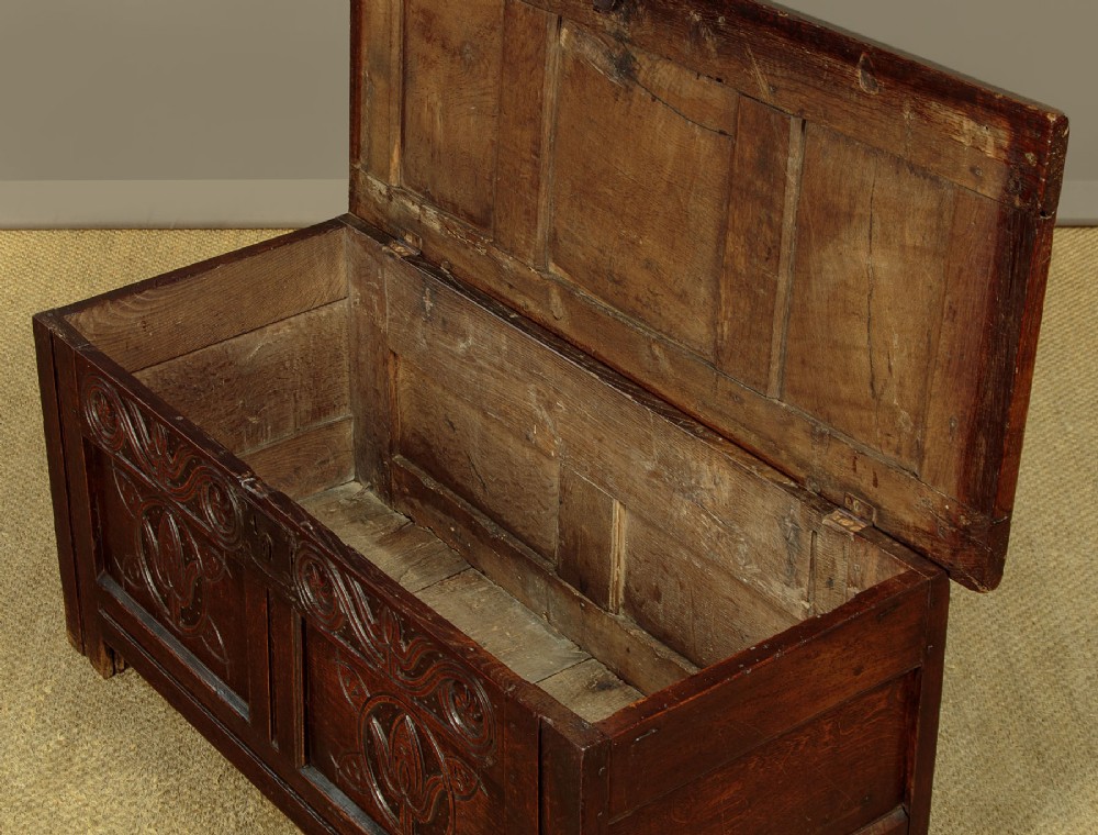 A dark oak coffer from circa 1700 featuring carved panel fronts with floral motifs and a hinged wooden top. View VIII