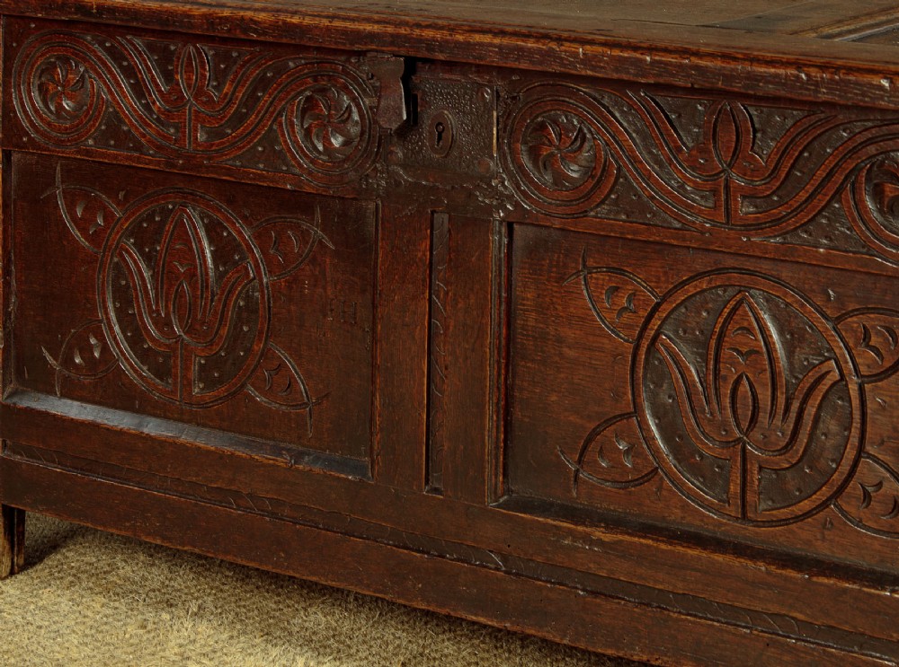 A dark oak coffer from circa 1700 featuring carved panel fronts with floral motifs and a hinged wooden top. View XI