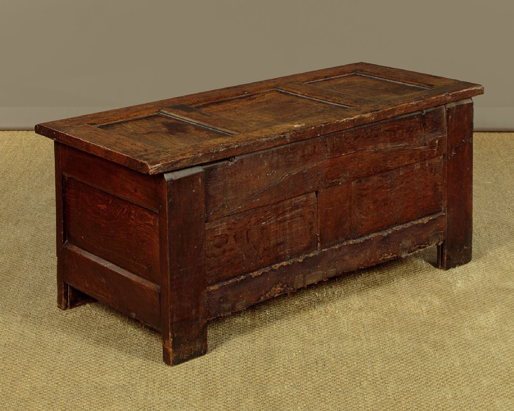 A dark oak coffer from circa 1700 featuring carved panel fronts with floral motifs and a hinged wooden top. View XIII