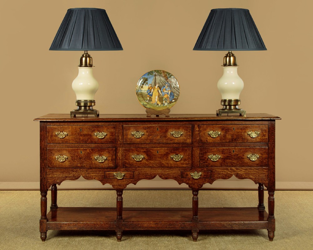 A Georgian oak Welsh dresser base featuring eight drawers with brass handles, a scalloped apron, turned front legs, and an open potboard lower shelf. View II