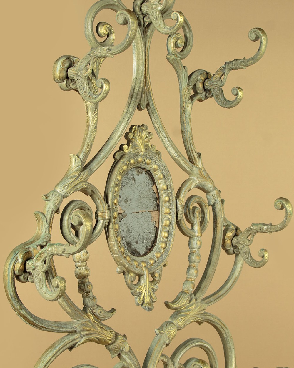 An ornate Victorian painted cast iron hall stand featuring scrollwork motifs, multiple coat hooks, a central oval mirror, and an umbrella drip tray base. View VI