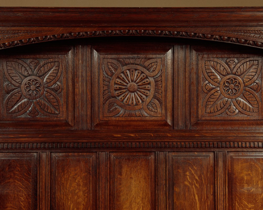 A dark oak canopy box settle featuring intricate carved floral panels, a tall fielded-panel back, and a lift-up storage seat base. View IV