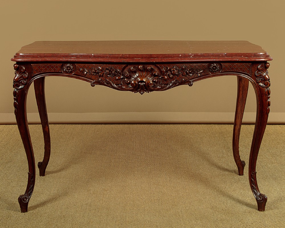 A late nineteenth-century carved walnut centre table with cabriole legs, Rococo frieze carving, and a rouge marble top. View II