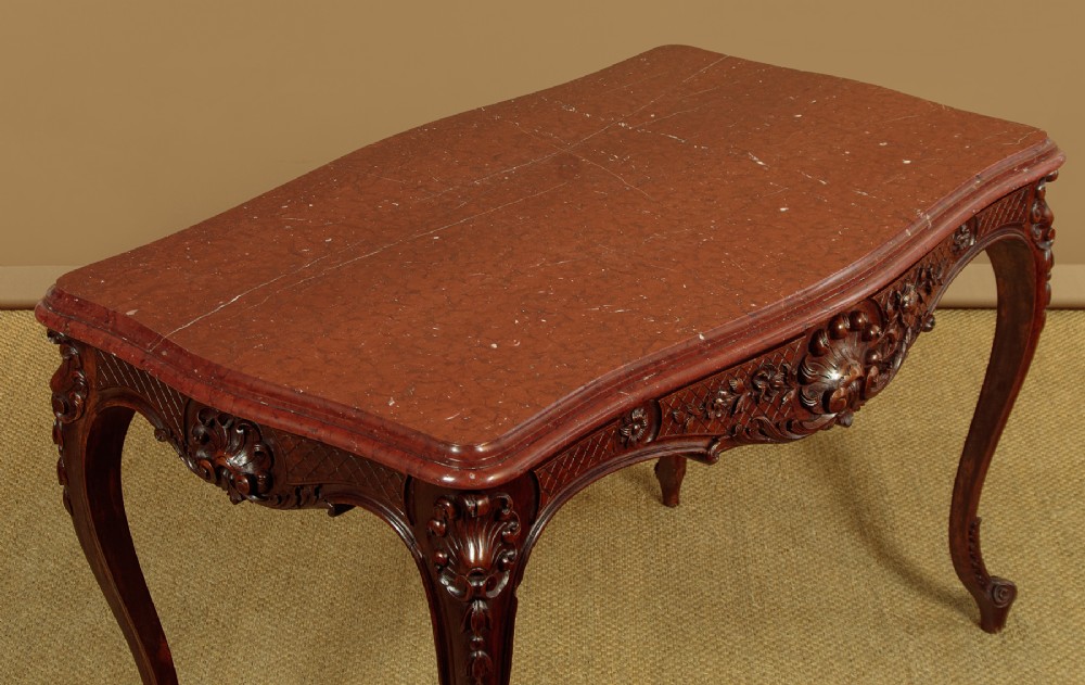 A late nineteenth-century carved walnut centre table with cabriole legs, Rococo frieze carving, and a rouge marble top. View III