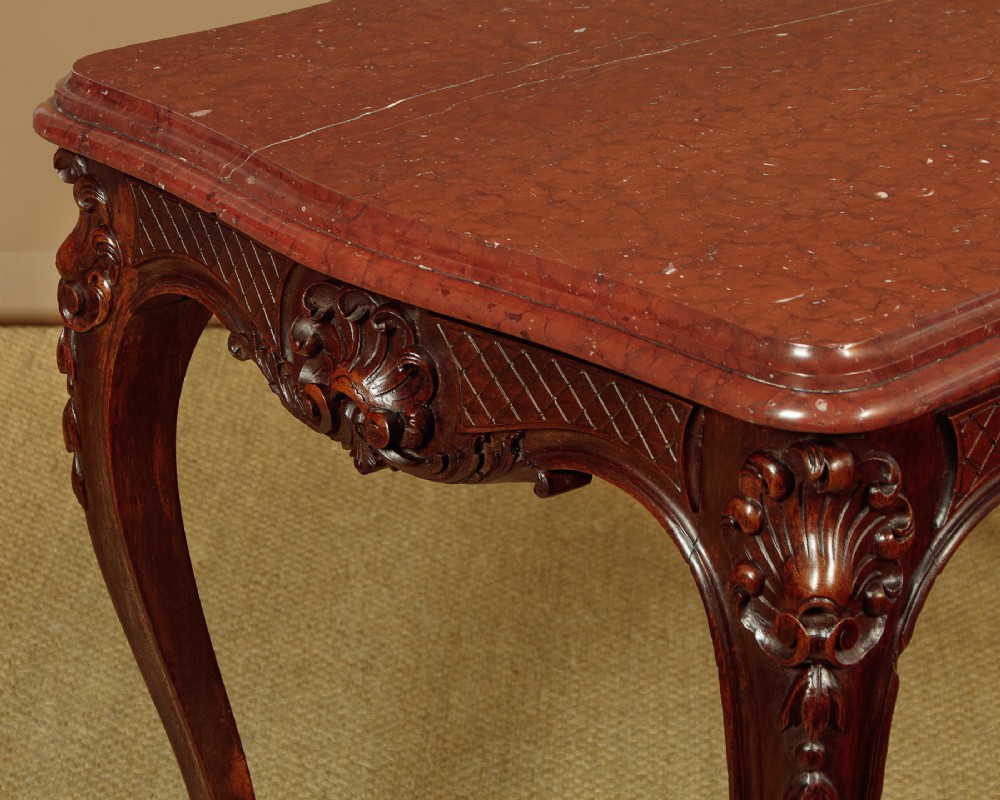 A late nineteenth-century carved walnut centre table with cabriole legs, Rococo frieze carving, and a rouge marble top. View IV