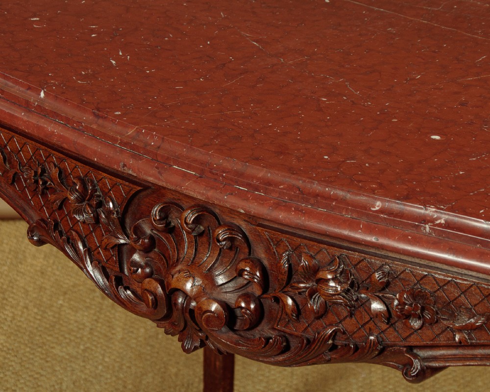 A late nineteenth-century carved walnut centre table with cabriole legs, Rococo frieze carving, and a rouge marble top. View V
