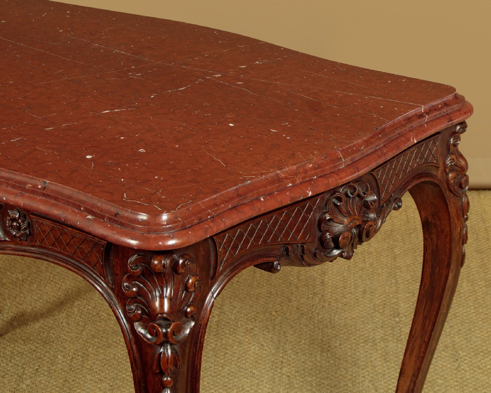 A late nineteenth-century carved walnut centre table with cabriole legs, Rococo frieze carving, and a rouge marble top. View VI
