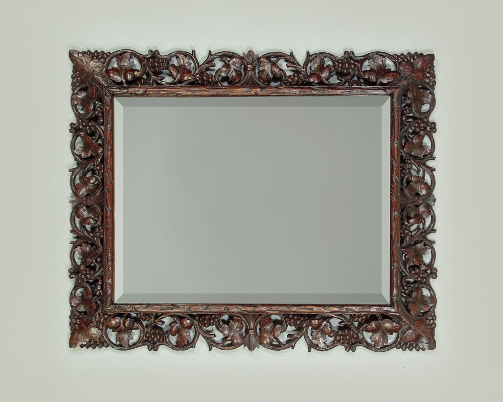 A rectangular dark oak wall mirror featuring intricate openwork carvings of grapevines and leaves framing a bevelled glass plate. View II
