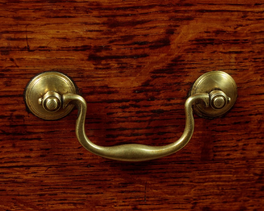 A long Georgian oak dresser base featuring five drawers with brass swan-neck handles, crossbanded drawer borders, a scalloped apron, and straight legs. View X