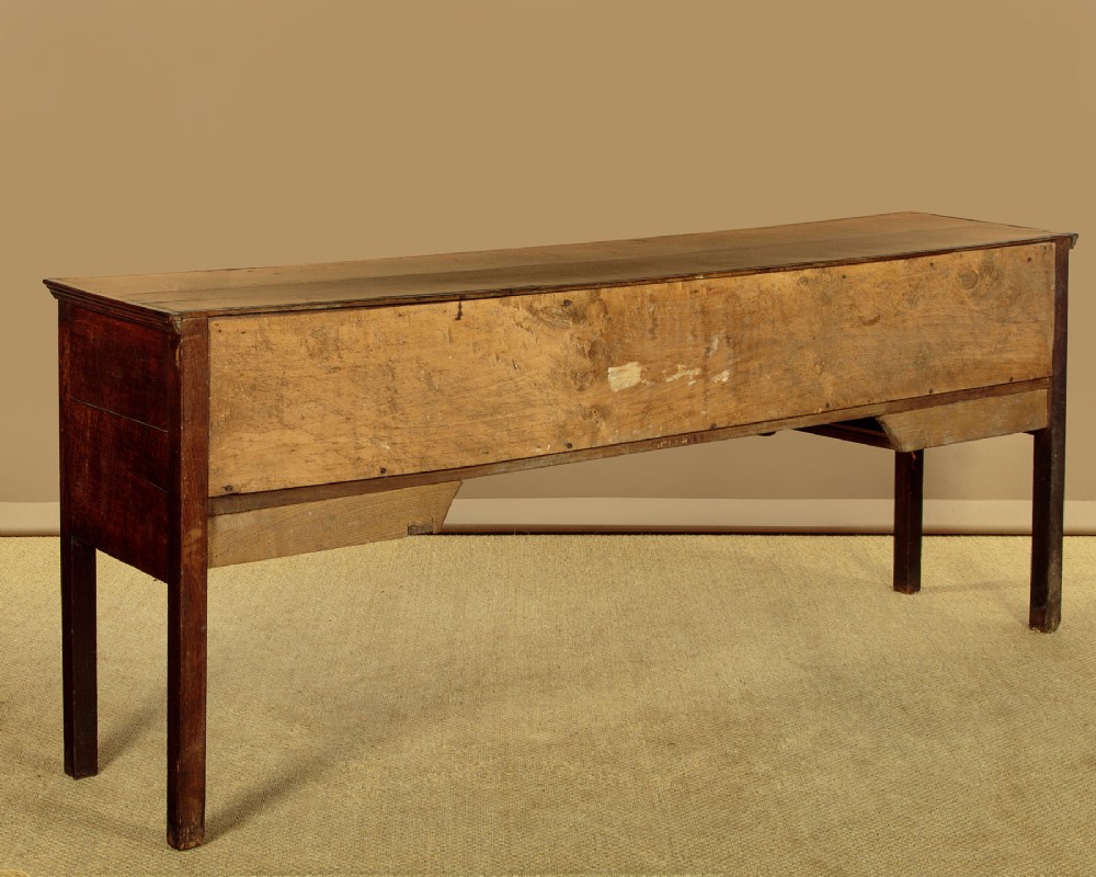 A long Georgian oak dresser base featuring five drawers with brass swan-neck handles, crossbanded drawer borders, a scalloped apron, and straight legs. View XIII