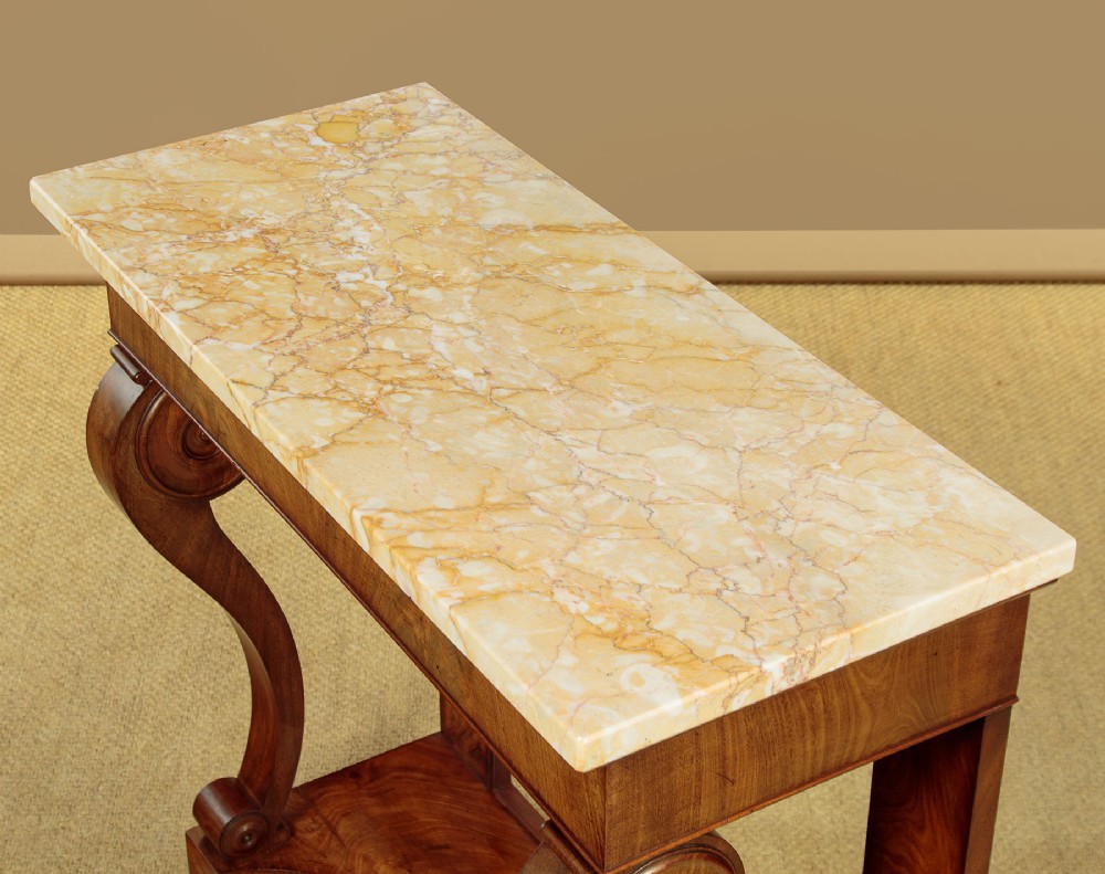 A late 19th-century mahogany console table featuring a light yellow marble top, S-scroll front supports with carved roundels, and a concave plinth base. View IV