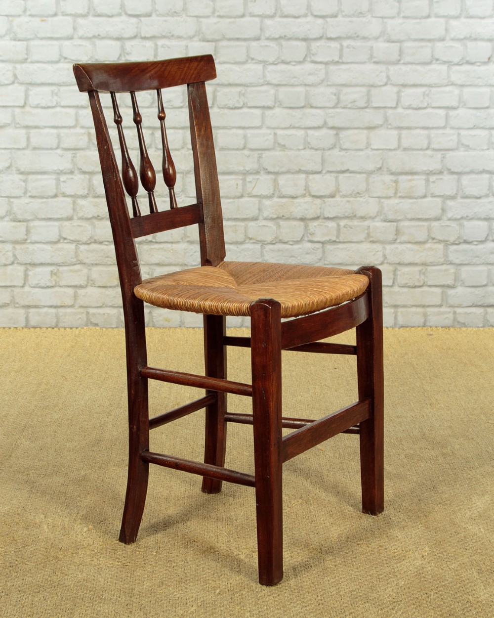 A set of four dark wood dining chairs featuring turned spindle backrests and hand-woven rush seats. View III
