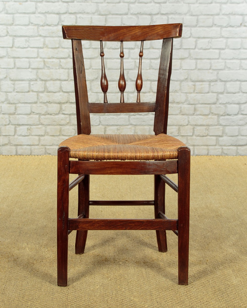 A set of four dark wood dining chairs featuring turned spindle backrests and hand-woven rush seats. View IV