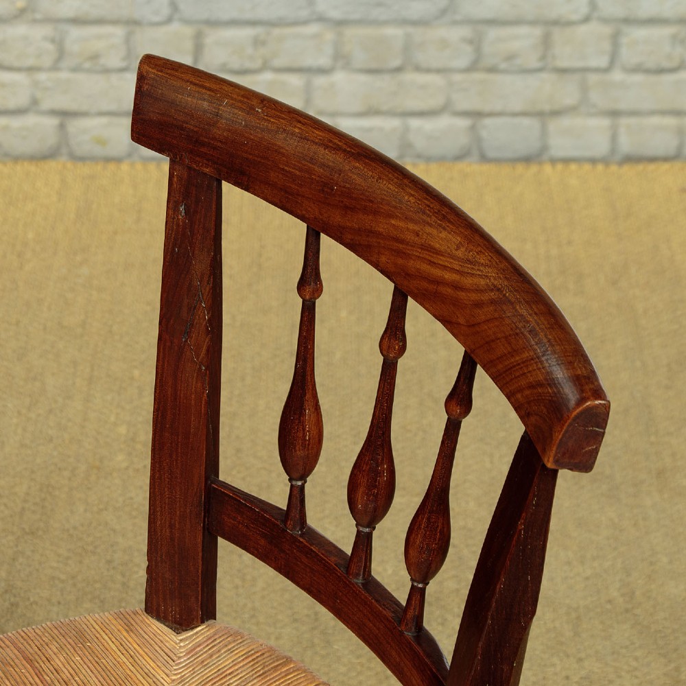 A set of four dark wood dining chairs featuring turned spindle backrests and hand-woven rush seats. View V