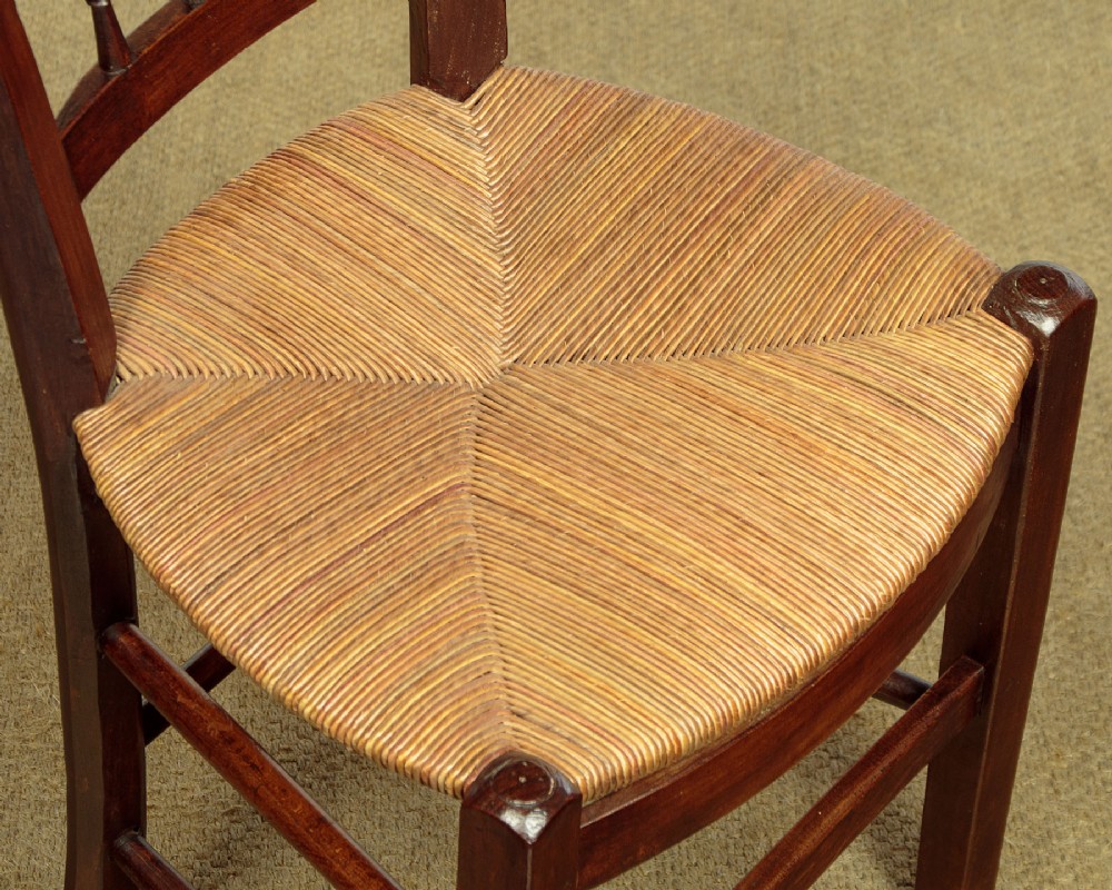 A set of four dark wood dining chairs featuring turned spindle backrests and hand-woven rush seats. View VIII