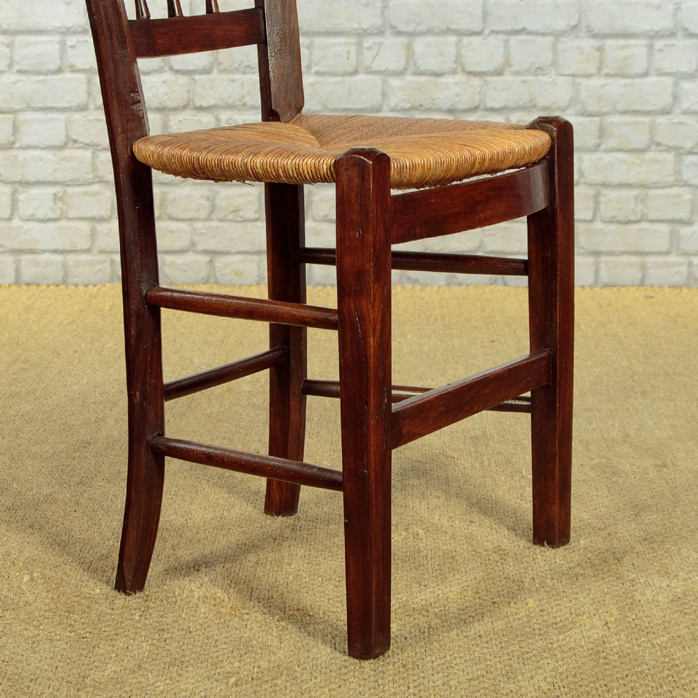 A set of four dark wood dining chairs featuring turned spindle backrests and hand-woven rush seats. View X
