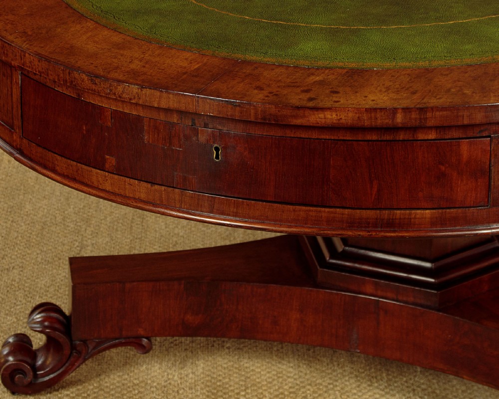An oval Victorian mahogany library table featuring a green gilt-tooled leather top, frieze drawers, and a central pedestal with carved scroll feet on castors. View VIII