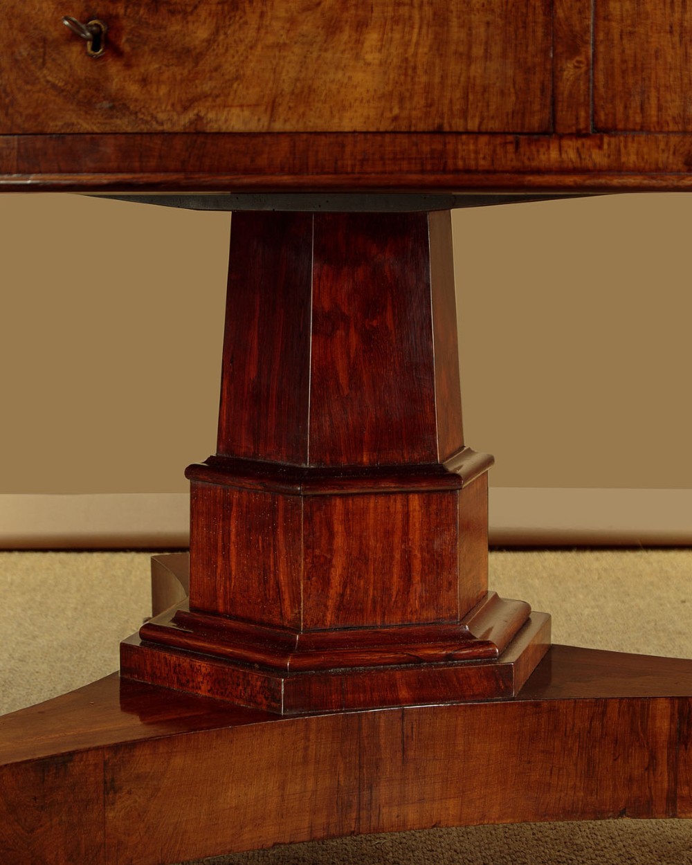 An oval Victorian mahogany library table featuring a green gilt-tooled leather top, frieze drawers, and a central pedestal with carved scroll feet on castors. View IX