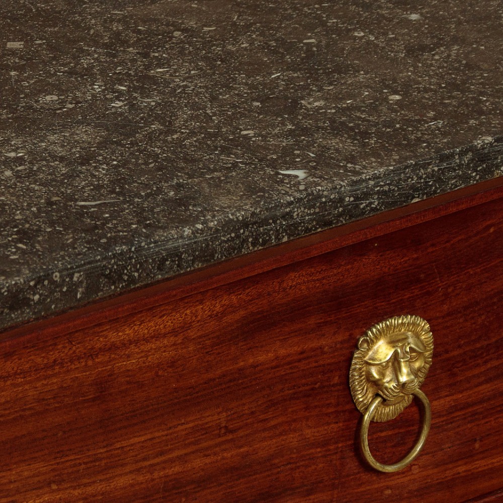 A French Empire mahogany commode featuring three long drawers, brass lion mask ring handles, carved claw feet, and a dark grey marble top. View VIII