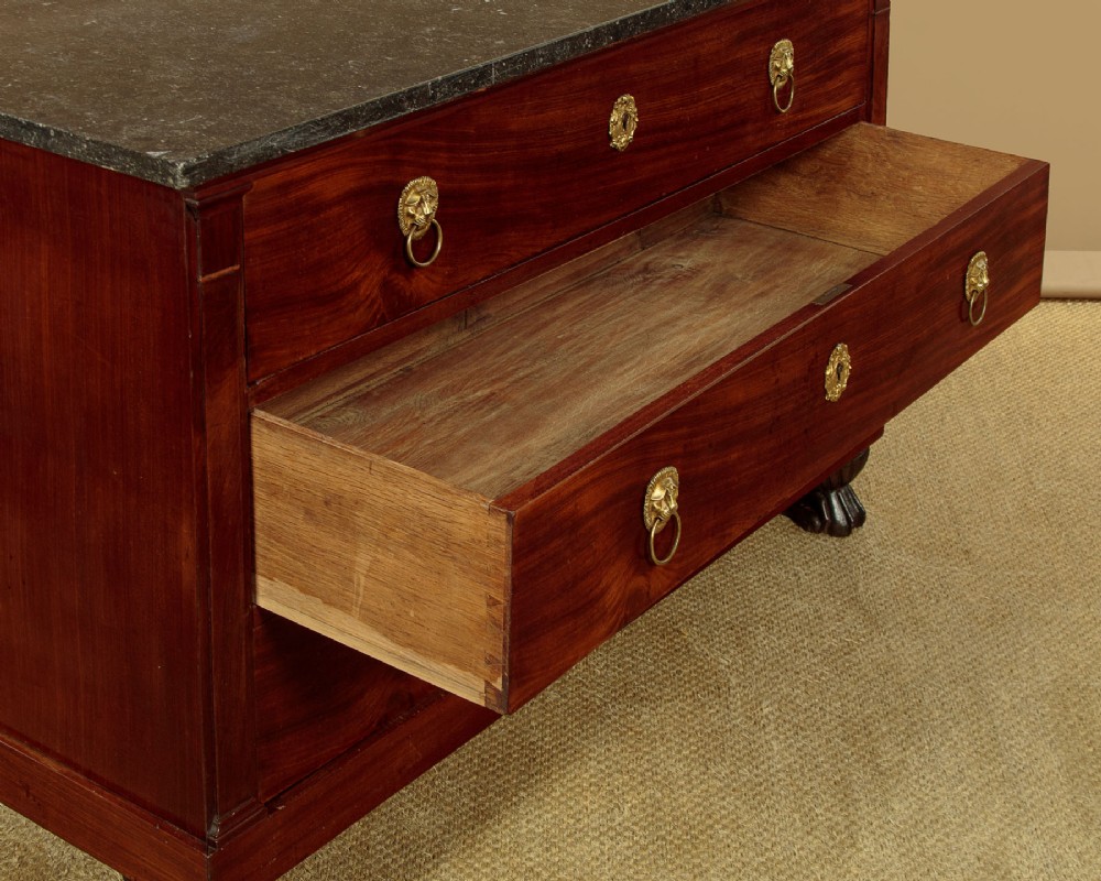 A French Empire mahogany commode featuring three long drawers, brass lion mask ring handles, carved claw feet, and a dark grey marble top. View XIII