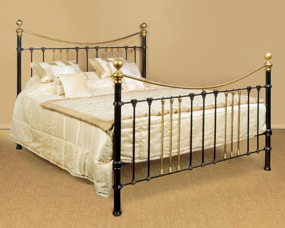 A late Victorian black iron and brass king-size bed frame featuring decorative brass finials, a dipped brass top rail, and vertical spindles. View II